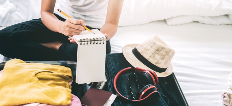 Woman packing her luggage and writing a travel checklist